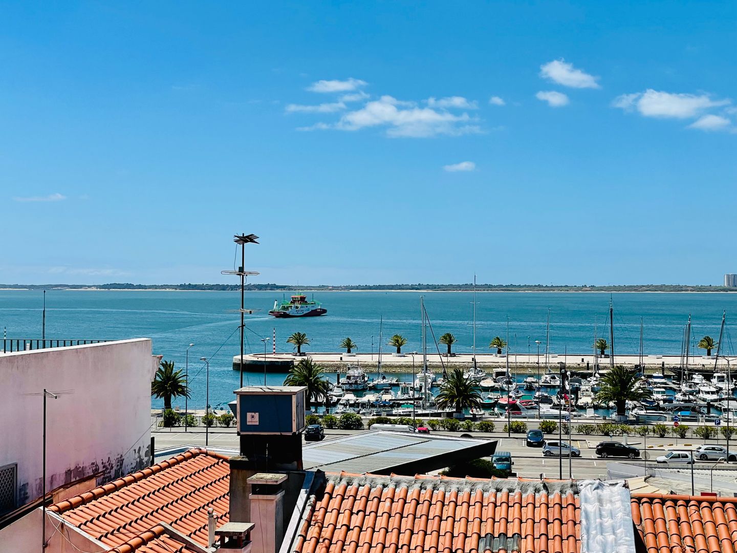 Una vista pintoresca de la Marina de Setúbal con barcos, tejados y el mar bajo un cielo azul.