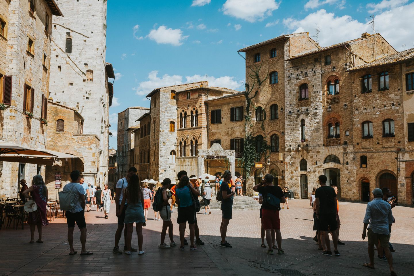Los turistas se reúnen en la medieval Piazza della Cisterna en San Gimignano, Toscana, Italia.