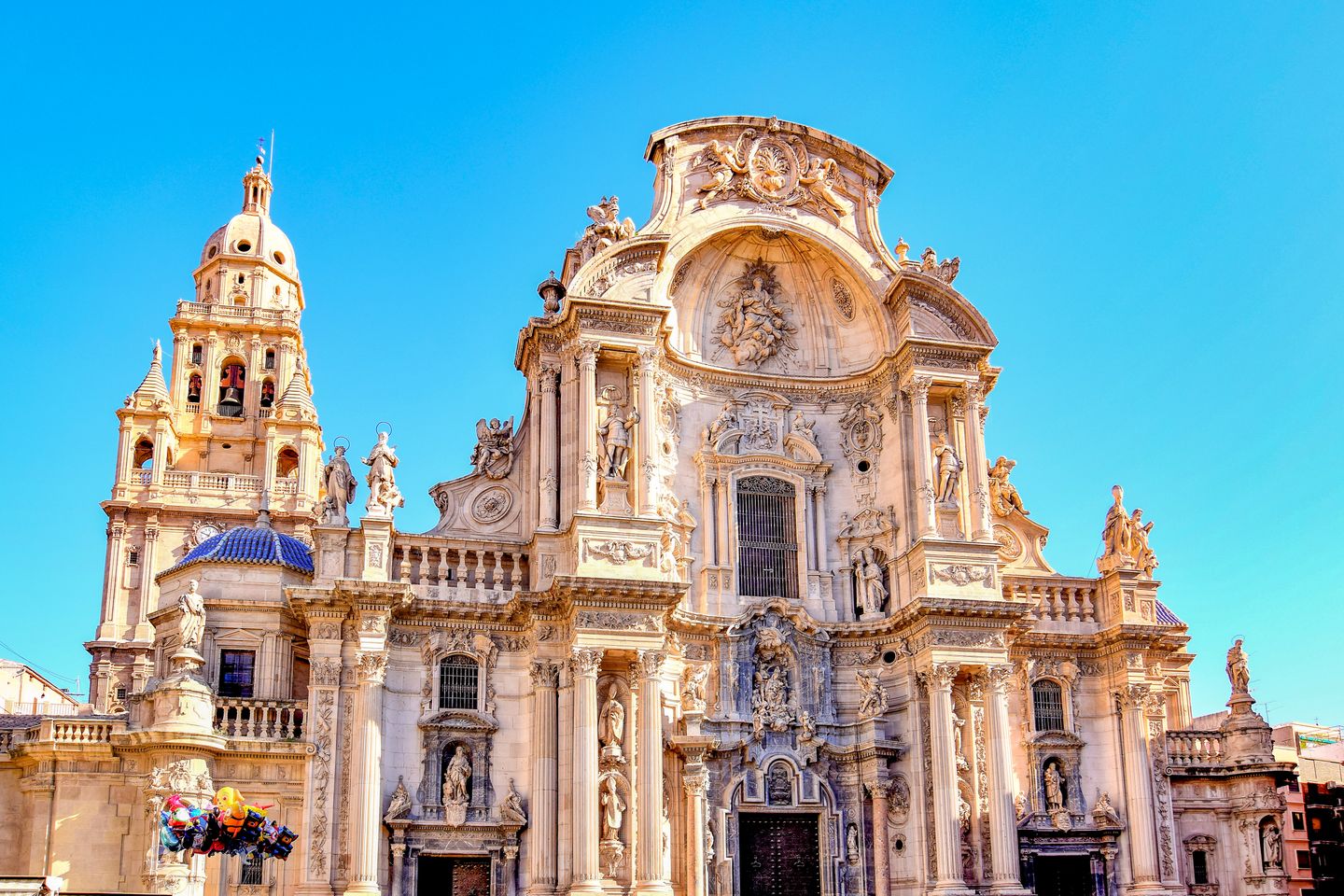 Arquitectura barroca intrincada de la Catedral de Murcia contra un cielo azul claro.