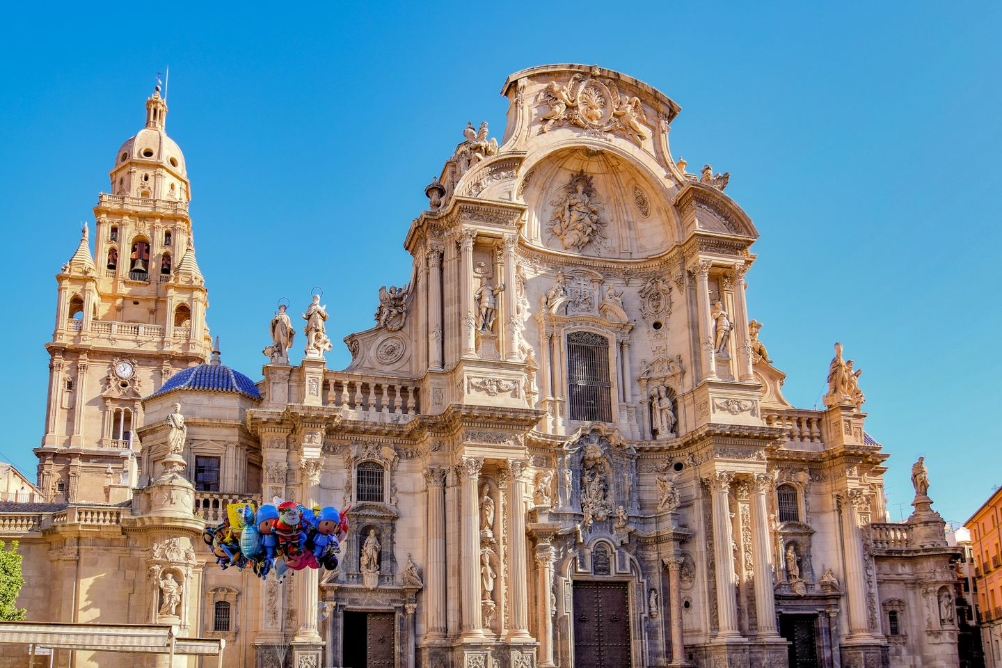 Catedral de Murcia, diseñada de manera intrincada, con esculturas y estatuas contra un cielo azul.