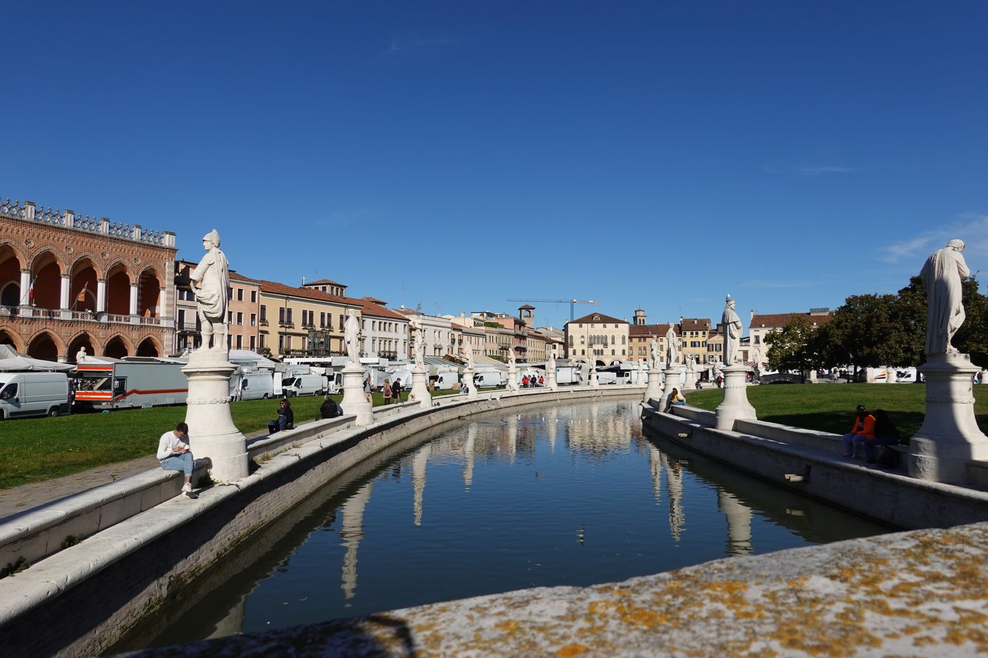 Escena encantadora de Prato della Valle en Padua, Italia, con estatuas y reflejo en el canal.