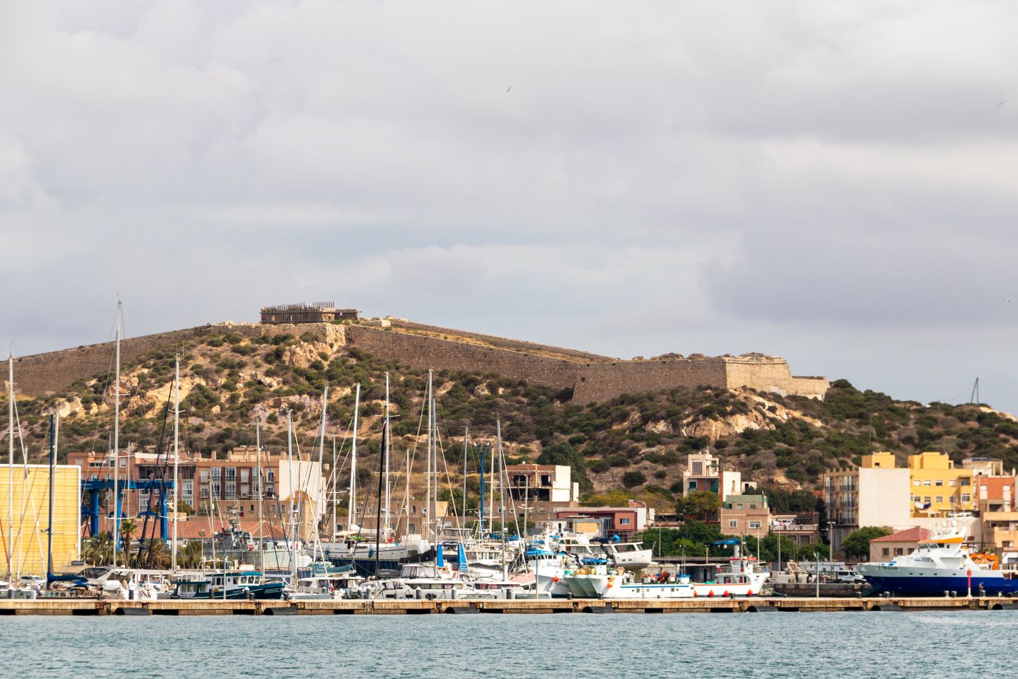 Un puerto pintoresco con yates y una fortaleza histórica en Cartagena, España.