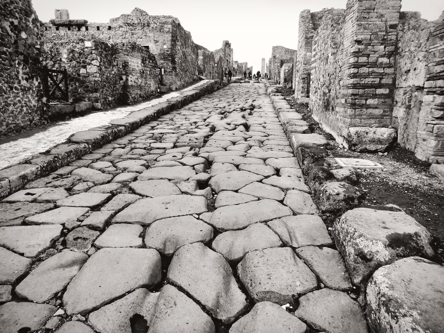 Explora la calle empedrada antigua preservada en Pompeya, Italia, mostrando la arquitectura romana.