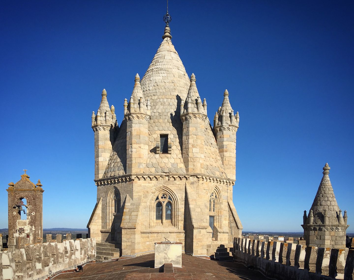Vista majestuosa de la aguja gótica de la catedral de Évora bajo un cielo azul claro. Una joya arquitectónica atemporal.