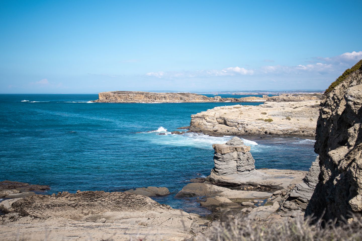 Explora la belleza robusta de la costa de Peniche con rocas iluminadas por el sol y un mar azul vibrante.