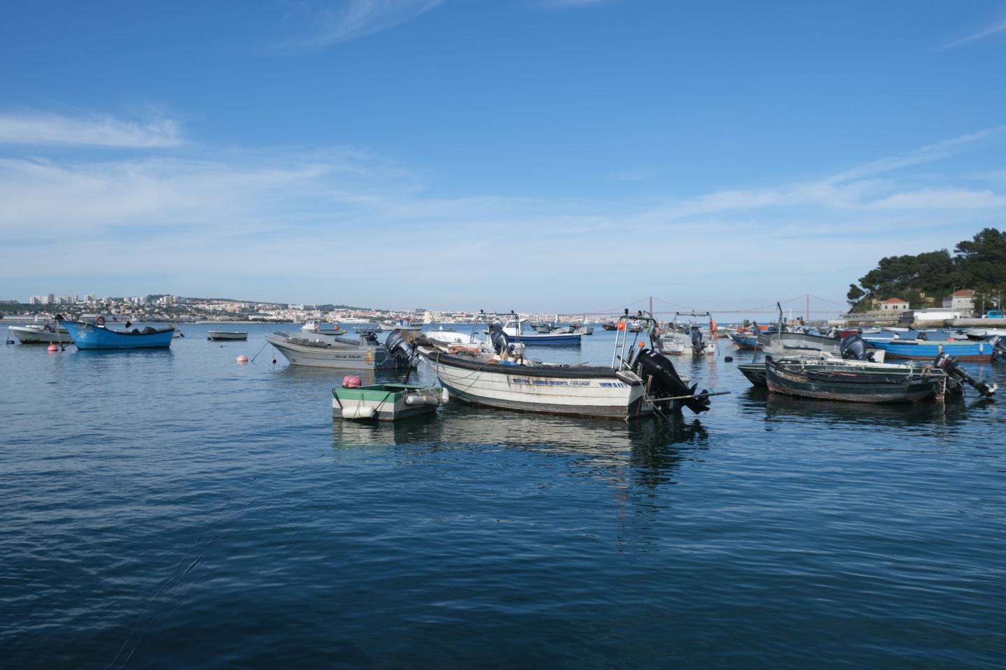 Bahía tranquila con barcos de pesca flotando en Setúbal, Portugal, bajo un cielo azul claro.