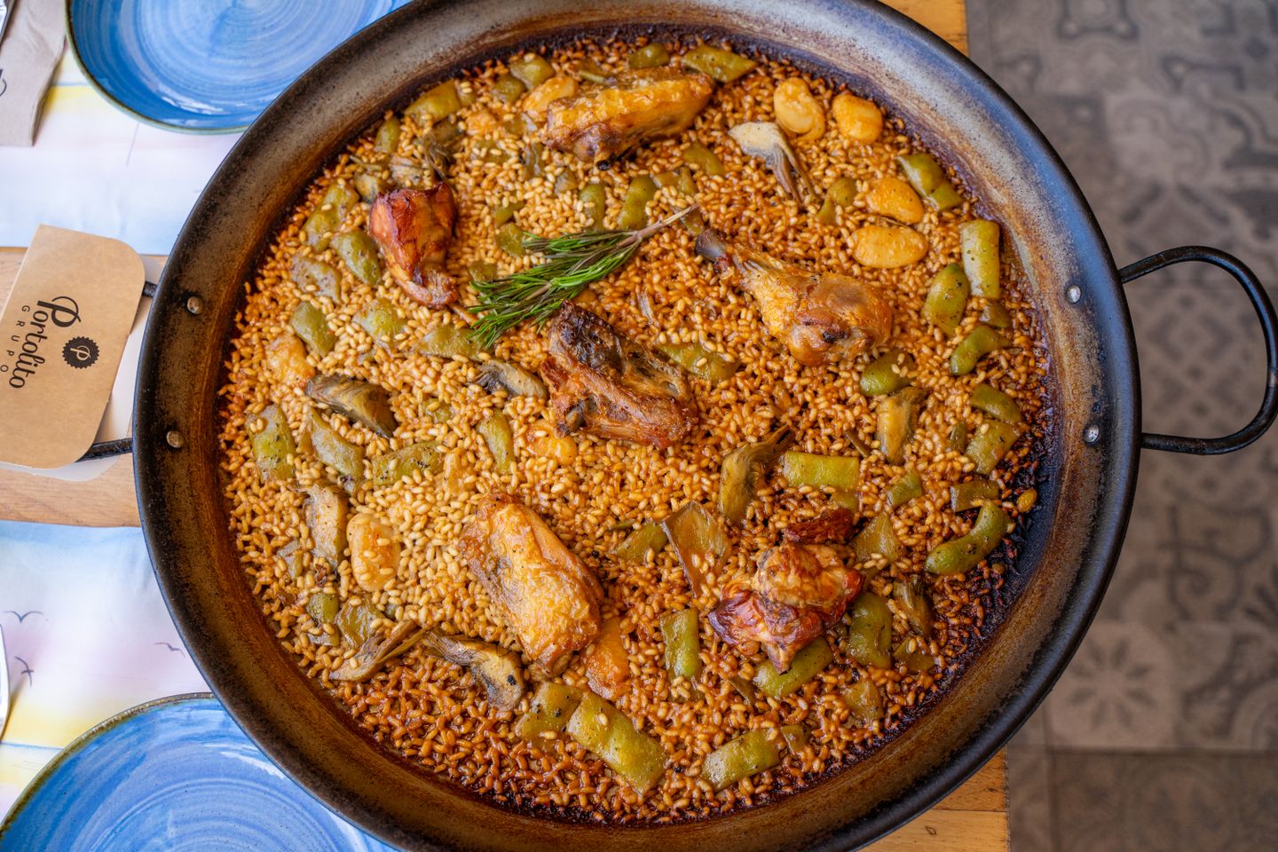 Paella auténtica de Valencia en una sartén con pollo, verduras y romero. Vista superior.