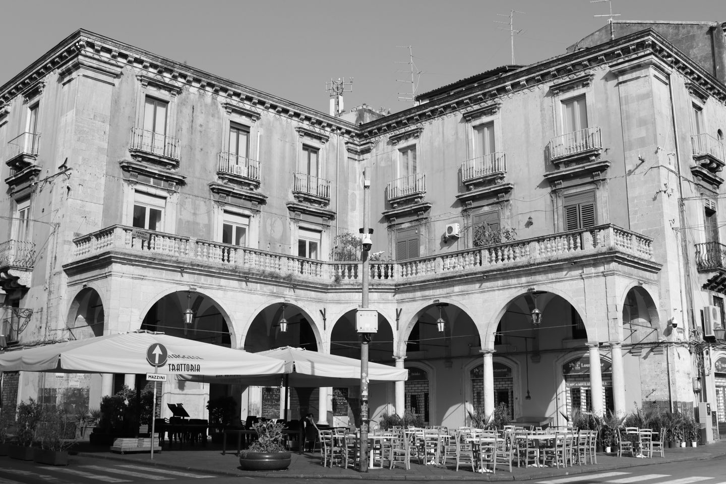 Edificio histórico elegante con arcos y café al aire libre en Catania, Sicilia.