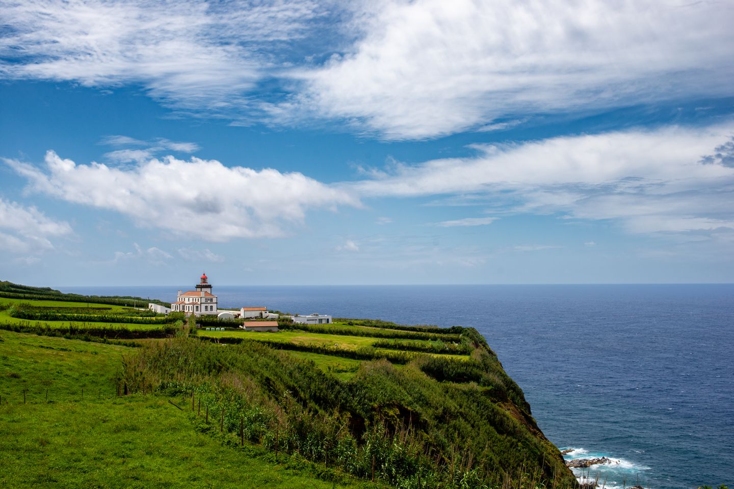 Pintoresco faro con exuberante vegetación y vista al mar en la isla de São Miguel, Azores.