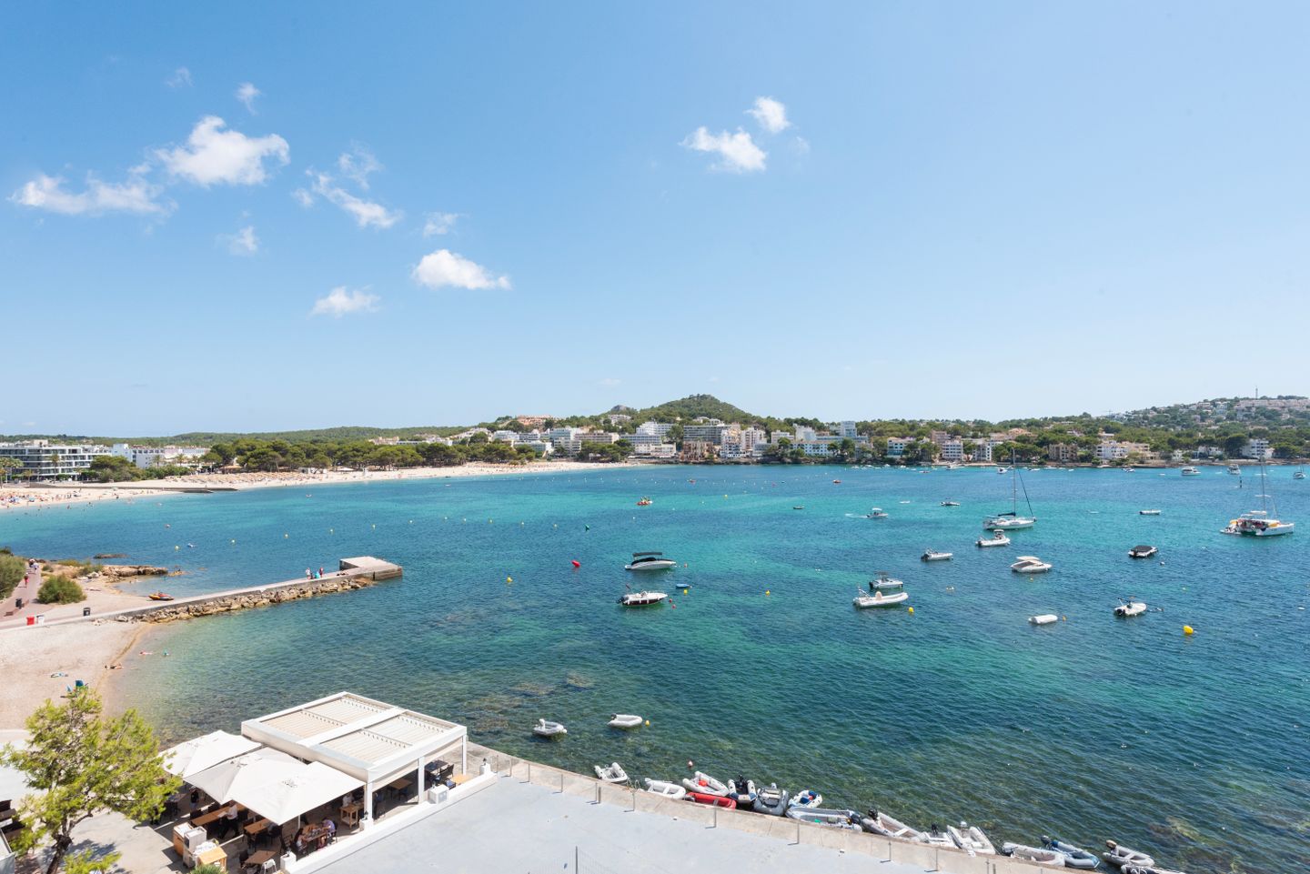 Vista pintoresca de la bahía de Santa Ponsa con barcos, aguas turquesas cristalinas y una playa de arena.