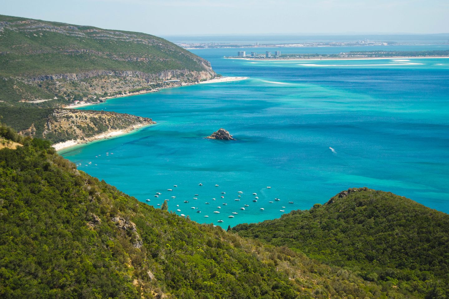 Impresionante vista aérea de la costa de Setúbal con aguas turquesas y exuberantes colinas verdes.