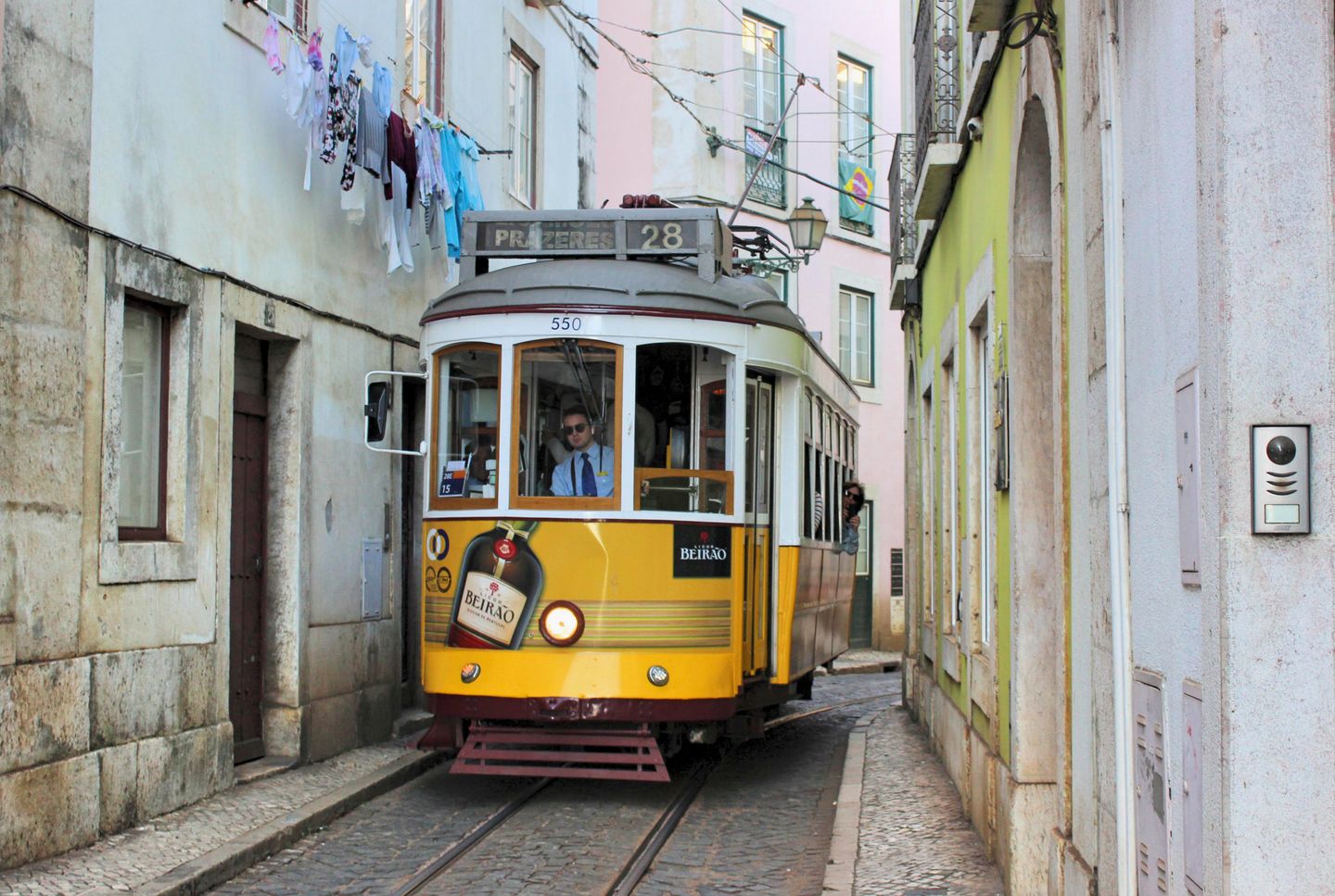 Tranvía amarillo histórico navegando por una calle estrecha de Lisboa, encapsulando el encanto tradicional de la ciudad.