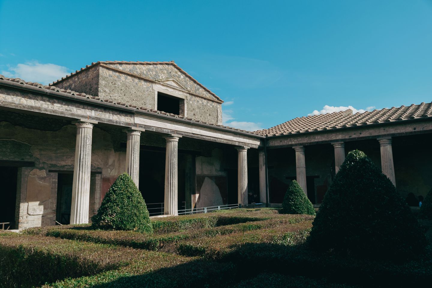 Explora las ruinas bien conservadas de un patio romano en Pompeya bajo un cielo azul claro.