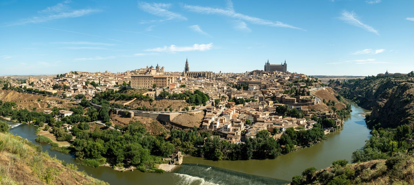 Impresionante vista panorámica de Toledo, España, que muestra la arquitectura histórica y el río Tajo bajo un cielo azul claro.