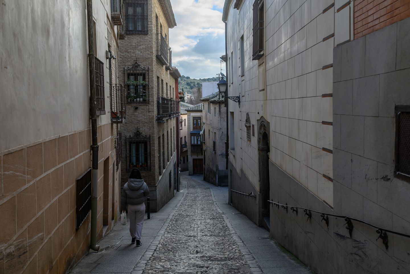 Una pintoresca calle estrecha y adoquinada en Toledo, España, con edificios históricos.