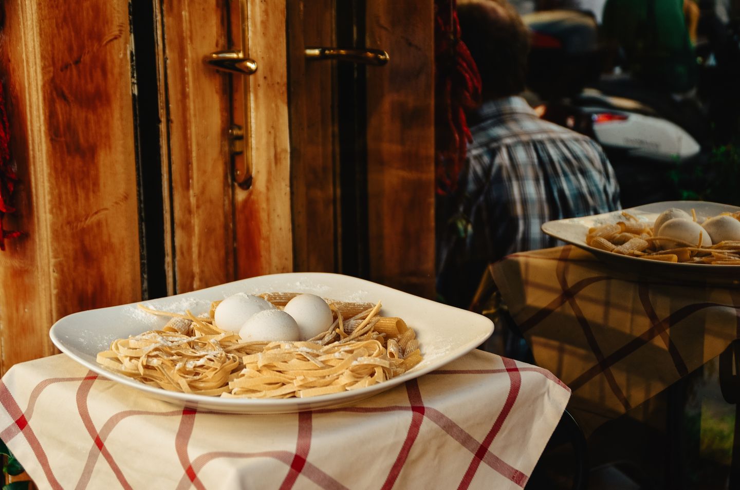 Un plato de pasta fresca con huevos se exhibe fuera de un restaurante en Roma, mostrando la cocina italiana.