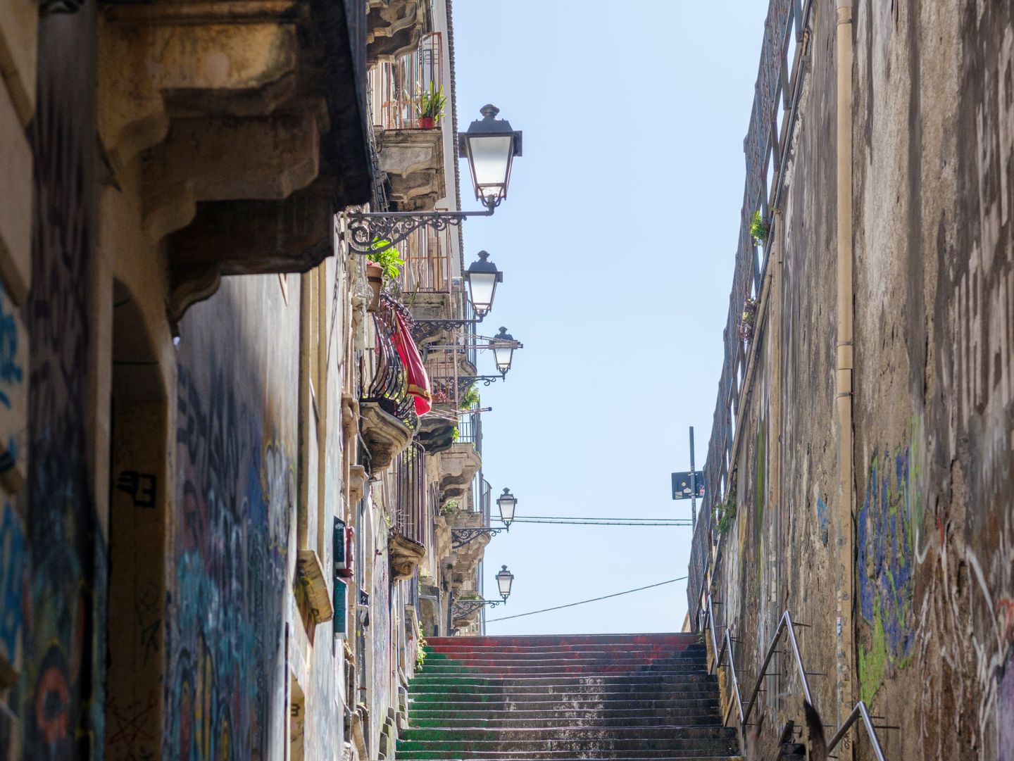 Encantadora vista de la escalera histórica con balcones y farolas que conduce al centro de la ciudad de Catania.