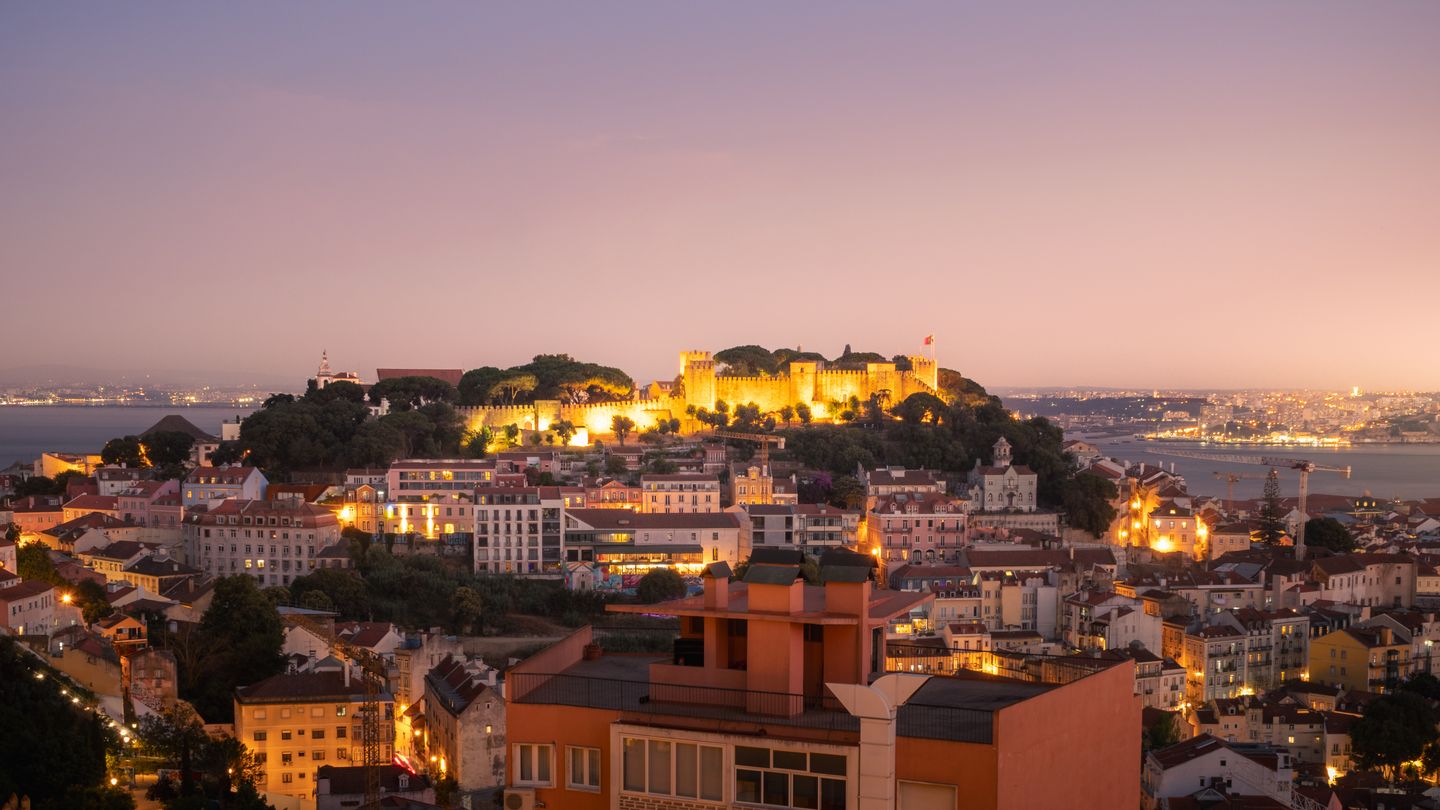Impresionante vista crepuscular de Lisboa, con el Castillo de San Jorge iluminado y el paisaje urbano a sus pies.