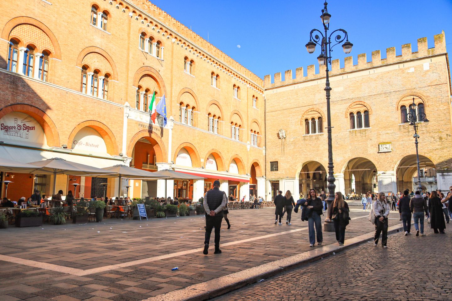 La bulliciosa Plaza Cavour en Rimini, Italia, con arquitectura histórica y personas disfrutando del día soleado.