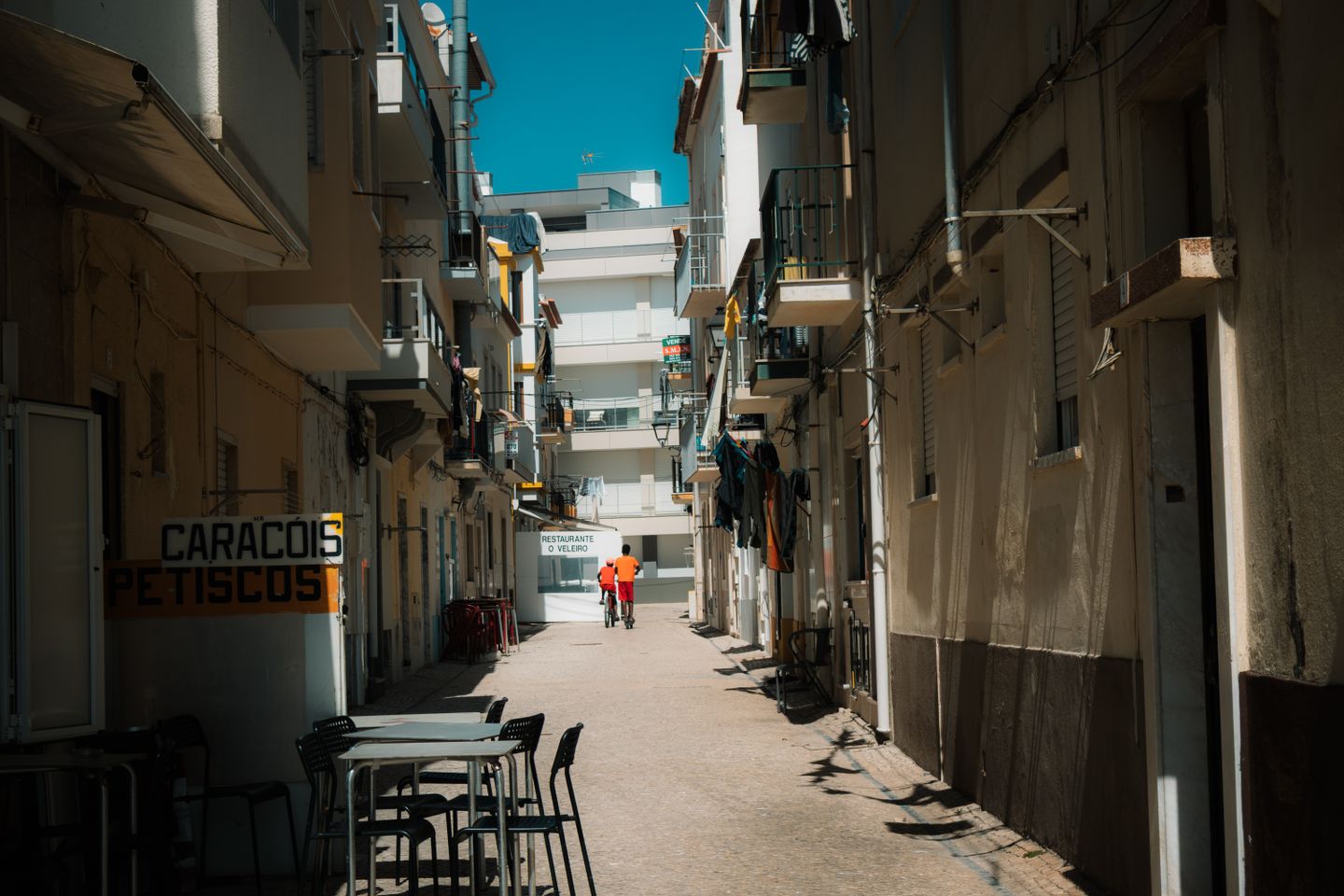 Callejón tranquilo en Nazaré, Portugal, con terraza y arquitectura tradicional.
