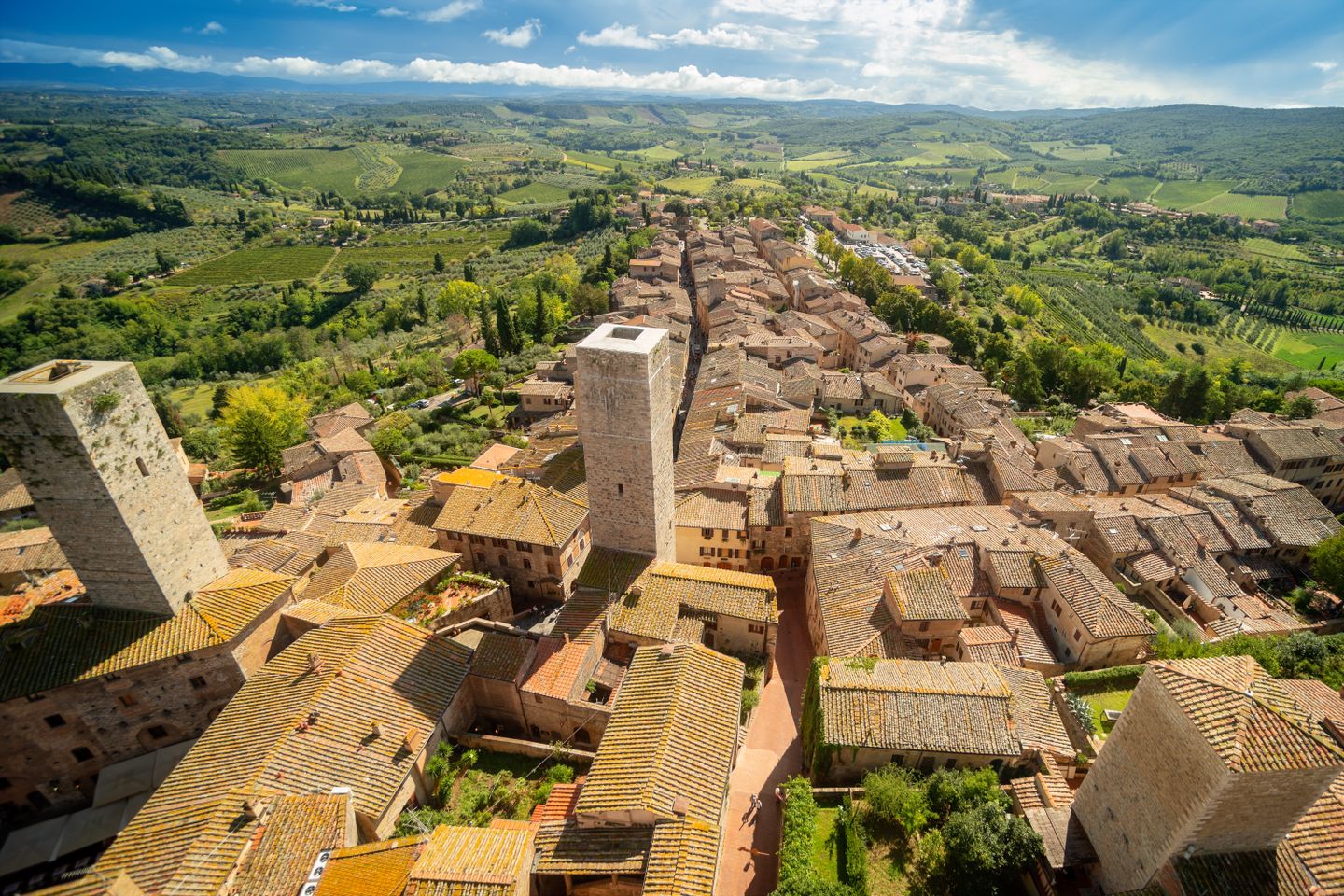Impresionante vista aérea de las torres medievales de San Gimignano y el verde paisaje toscano bajo un cielo despejado.