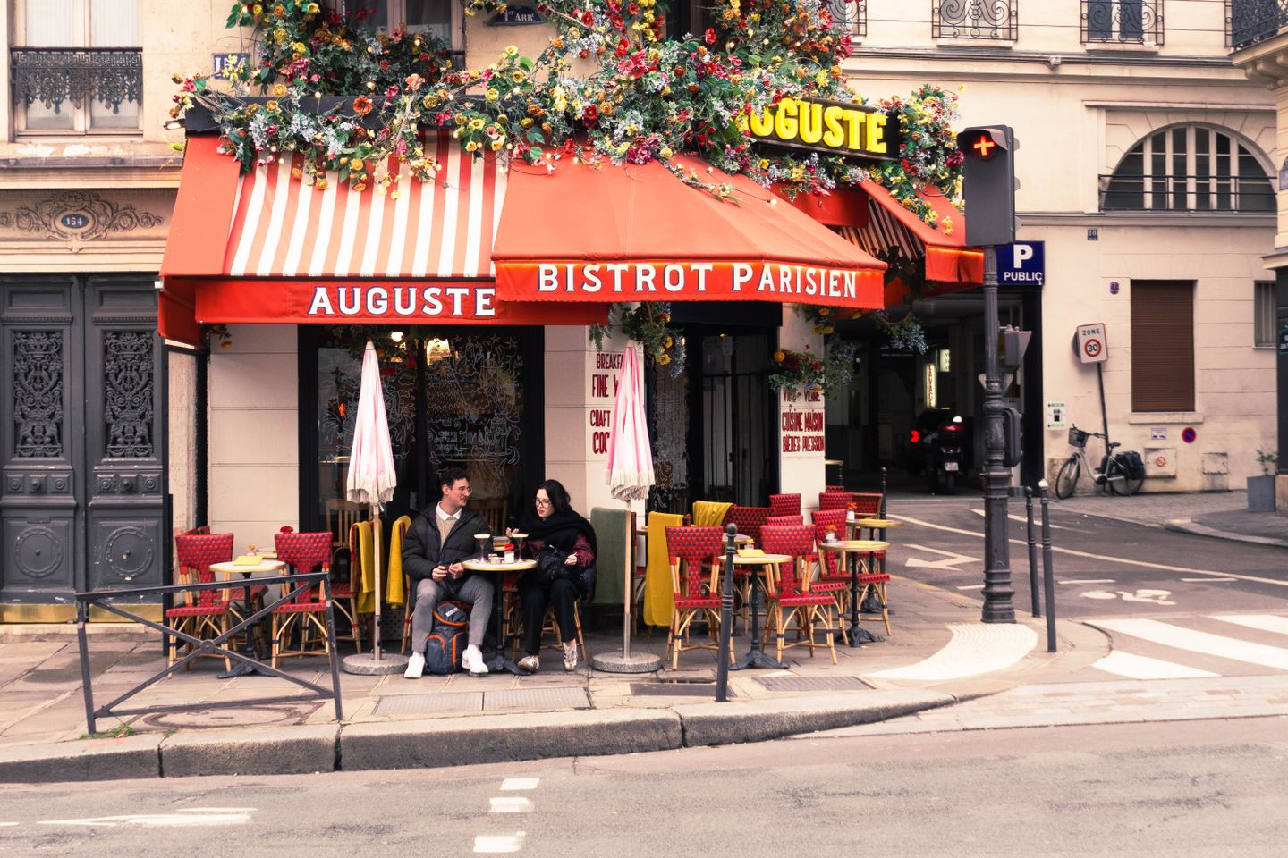 Una encantadora escena callejera parisina con gente disfrutando de un café en la terraza de una cafetería en París.