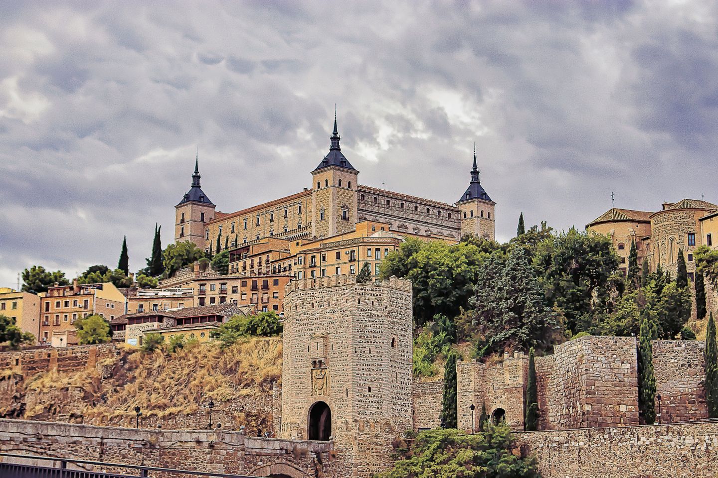 Impresionante vista del Alcázar de Toledo, España, con nubes dramáticas arriba, mostrando arquitectura histórica.