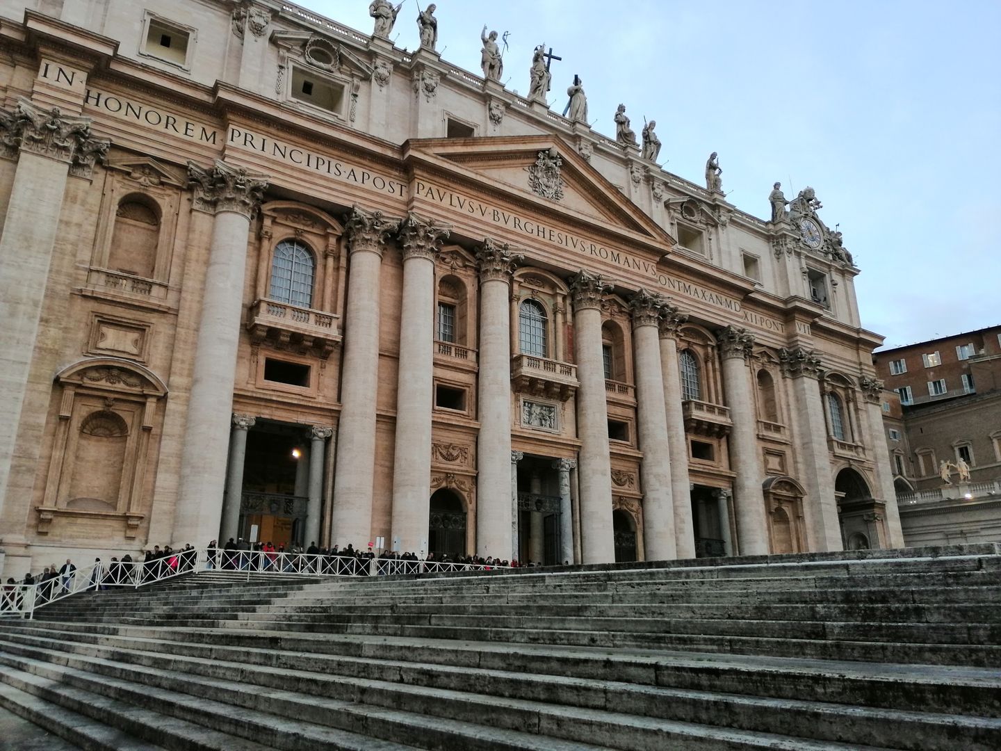 Fachada majestuosa de la Basílica de San Pedro con grandes columnas y detalles históricos en la Ciudad del Vaticano.