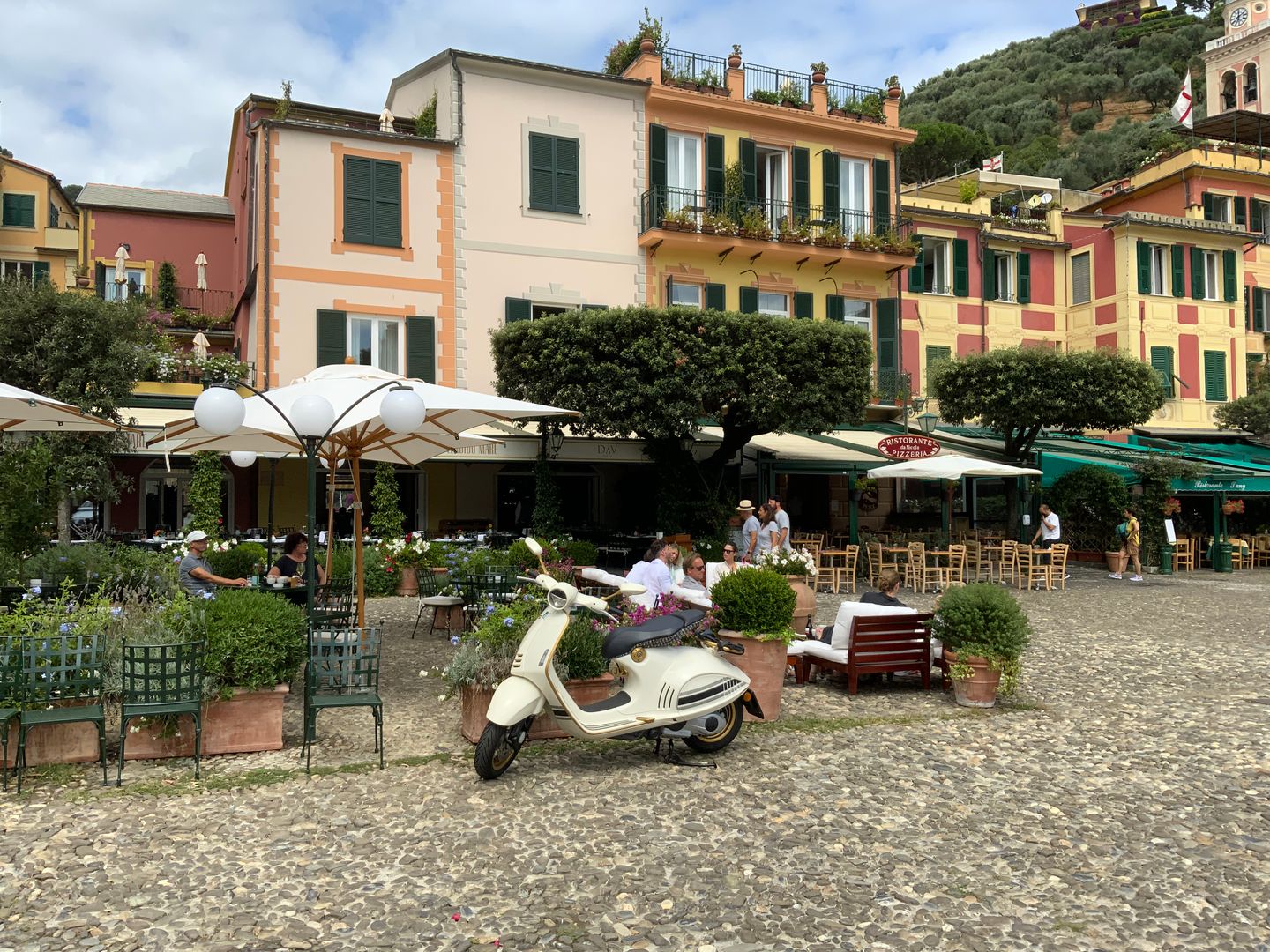Escena urbana encantadora en Portofino, Italia, con una cafetería pintoresca y una scooter clásica.