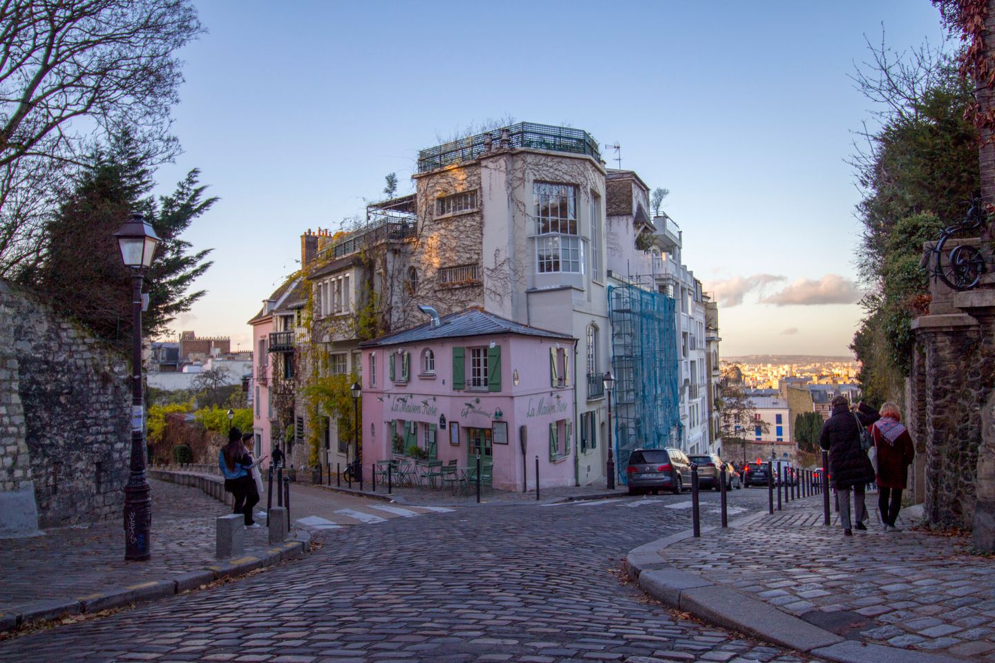 Hermosa calle empedrada con La Maison Rose en Montmartre, París, mostrando arquitectura clásica y vibrante vida callejera.