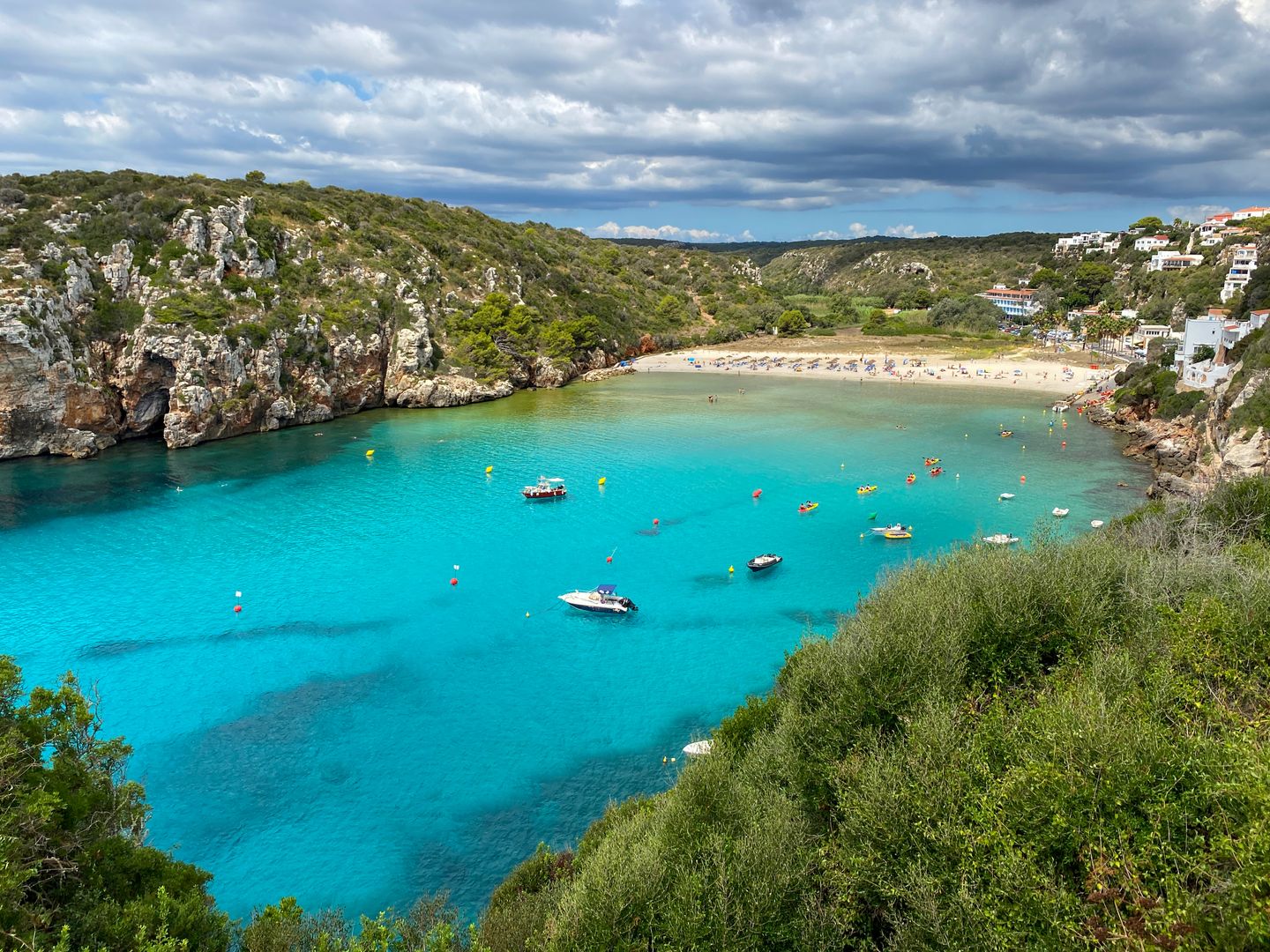 Impresionante toma aérea de la vibrante playa Cala en Porter en Menorca, mostrando aguas turquesas y acantilados escarpados.